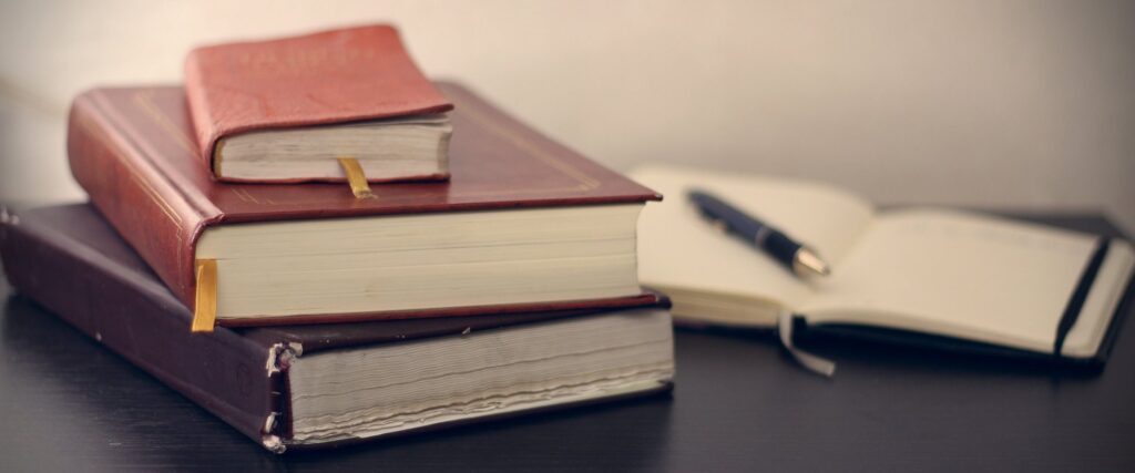 stock photo: close-up shot of a stacked leather books & an open journal on a wooden desk